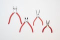 Different sizes of red pliers on a wooden background. Top view of repairing work tools on a wooden table Royalty Free Stock Photo