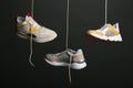 Different sneakers hanging on black background.