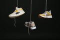 Different sneakers hanging on black background.