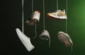 Different sneakers hanging on dark background.