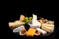 Different sorts of cheese set. Cheese platter with various cheese, with grapes, nuts, cheese knife and spices, black tiled Royalty Free Stock Photo