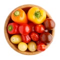 Different sorts of cherry tomatoes and multi colored little sweet peppers in wooden bowl isolated on white background. Top view Royalty Free Stock Photo