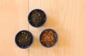 Different sorts of tea leaves in bowls on wooden background. Top view image