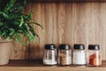 Different spices in glass jars on wooden shelf. Luxury modern kitchen furniture and wooden table top. Space for text. Spices and Royalty Free Stock Photo