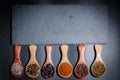 Different spices, peppers, coriander, sesame seeds and others for cooking are in wooden spoons on a black background Royalty Free Stock Photo