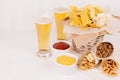 Different spicy mexican snacks and sauces - ketchup, curry - in bowl, cold lager beer on white wooden board.