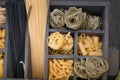 Different stuffed pasta such as fusillini, sedani rigati, spaghetti, linguine, fettuccine in rustic old wooden box over on wooden Royalty Free Stock Photo