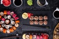 Different sushi rolls  with fish and  shiitake mushrooms  served  at black dish with rise at black table. flat lay Royalty Free Stock Photo