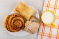 Sweet pastry in dish, cup with milk on napkin on wooden table. Top view Royalty Free Stock Photo