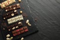 Different tasty chocolate bars with nuts and freeze dried raspberry on black table, flat lay. Space for text Royalty Free Stock Photo