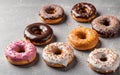 Different tasty glazed donuts on grey background. Sweet food, calories, holiday, birthday.