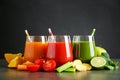 Different tasty juices and fresh ingredients on grey table against black background