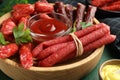 Different thin dry smoked sausages, parsley and sauces on green wooden table, closeup Royalty Free Stock Photo