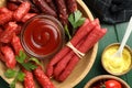 Different thin dry smoked sausages, parsley and sauces on green wooden table, flat lay Royalty Free Stock Photo