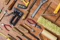 Different tools with wooden handles for repair: pliers, glass cutters, chisels, platens on a wooden background