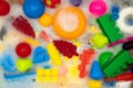 Different toys in soapy foam. Clean toys protect children from viruses and bacteria. Background from bright children`s toys in th
