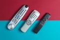 Different TV remotes on a red-blue background. Royalty Free Stock Photo