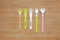 Different type of plastic spoons for babies on wood board background Royalty Free Stock Photo