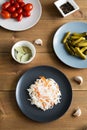 Different types appetizers flat lay on wooden background. Plates with sauerkraut cabbage and pickled cucumbers and tomatoes.