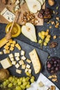Different types of cheese on board, olive, fruits, almond and wine glasses on black stone table Royalty Free Stock Photo