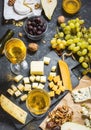 Different types of cheese on board, olive, fruits, almond and wine glasses on black stone table Royalty Free Stock Photo