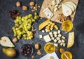 Different types of cheese on board, olive, fruits, almond and wine glasses on black stone table Royalty Free Stock Photo