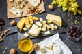 Different types of cheese on board, olive, fruits, almond and wine glasses on stone table Royalty Free Stock Photo