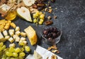 Different types of cheese on board, olive, fruits, almond and wine glasses on stone table Royalty Free Stock Photo