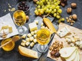 Different types of cheese on board, olive, fruits, almond and wine glasses on stone table Royalty Free Stock Photo