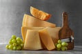 Different types of cheese, slicer and grapes on grey table Royalty Free Stock Photo