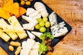 Different types of cheeses on black board.Assorted cheese on a black ceramic kitchen board with grapes, olives and nuts Royalty Free Stock Photo