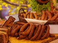 Different types of homemade smoked dry sausages hanging on a dark wooden background. Assortment of delicious deli meats, Salami