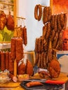 Different types of homemade smoked dry sausages hanging on a dark wooden background. Assortment of delicious deli meats, Salami