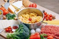 Different types of italian pasta on a wooden background with various ingredients for cooking traditional italian dishes Royalty Free Stock Photo