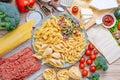 Different types of italian pasta on a wooden background with various ingredients for cooking traditional italian dishes Royalty Free Stock Photo