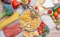 Different types of italian pasta on a wooden background with various ingredients for cooking traditional italian dishes Royalty Free Stock Photo