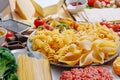 Different types of italian pasta on a wooden background with various ingredients for cooking traditional italian dishes Royalty Free Stock Photo