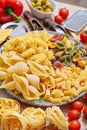 Different types of italian pasta on a wooden background with various ingredients for cooking traditional italian dishes Royalty Free Stock Photo