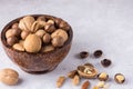 Different types of nuts - walnuts, almonds, macadamia in a bowl of coconut on a gray background.