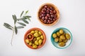 Different types of olives green and black in bowls on white table. Top view, close-up, copy space Royalty Free Stock Photo