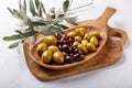 Different types of olives green and black on wooden plate on white table. Close-up Royalty Free Stock Photo