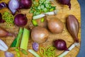 Different types of onion on wooden table. Onions, shallots, red and spring onions variety