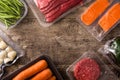 Different types of packaged food. Beef,vegetables and seafood on wooden table.