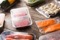 Different types of packaged food. Meat, green beans, carrots and salmon on wood