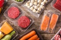 Different types of packaged food. Meat, green beans, carrots and salmon on wooden table.