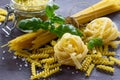 Different types of pasta with basil on the kitchen wooden table. The concept of Italian food Royalty Free Stock Photo