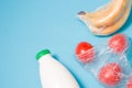 different types of plastic packaging on a blue background, a package with tomatoes, bananas wrapped in a film and a bottle of milk Royalty Free Stock Photo