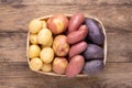 Different types of potatoes in a box on wooden rustic table