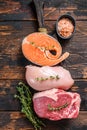 Different types of raw meat steaks Beef striploin, salmon and chicken breast. Dark wooden background. Top view Royalty Free Stock Photo