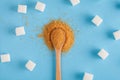 Different types of sugar, brown sugar in wooden spoon and white sugar cubes on pastel blue background, top view Royalty Free Stock Photo